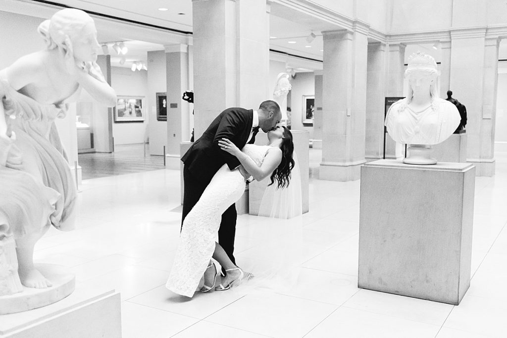 The couple kisses passionately in the sculpture gallery