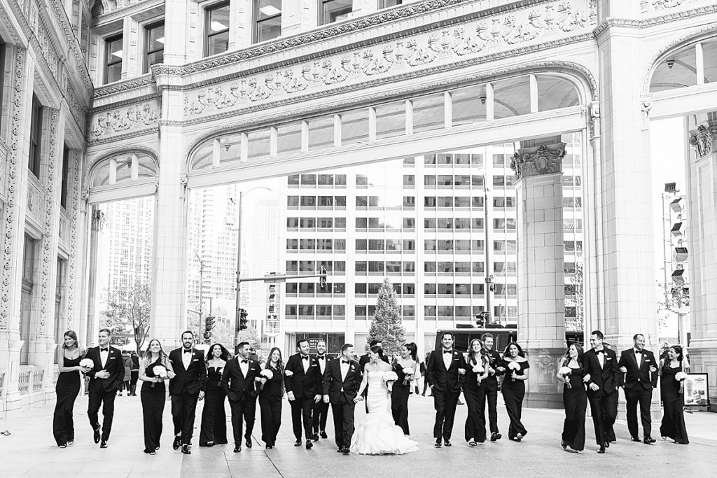 A large bridal party all in black tie attire