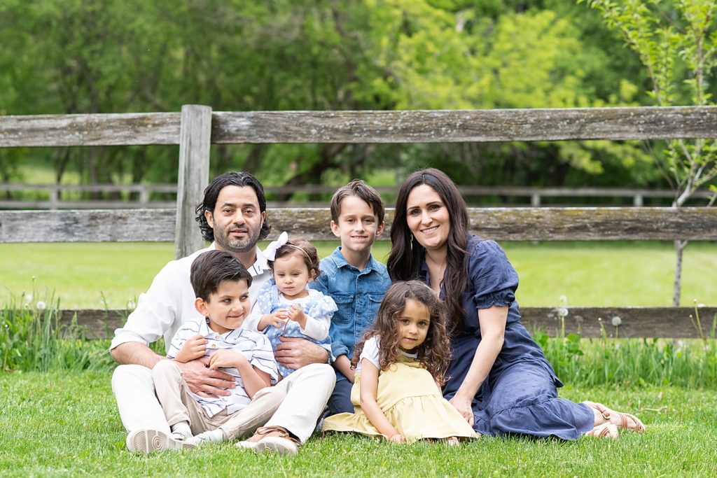 Family photos in front of a wooden fence, family of six