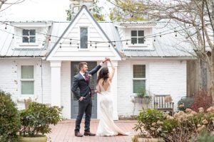 Bride and groom dancing in front of white building at Long Hollow Gardens in Nashville, Tennessee