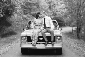 Black and white photo of man and woman both sitting on top of a vintage Chevrolet truck during their anniversary session
