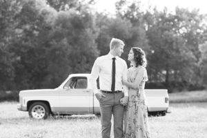 Man and woman posing together during anniversary session with a vintage Chevy truck in the background.