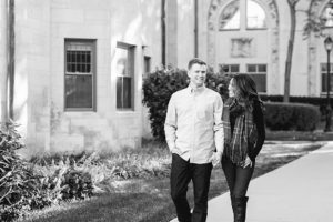 Black and white image from Northwestern University engagement photo session. Man and woman walking together with the woman holding on to the man's arm.