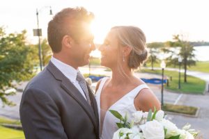 Photo of bride and groom with faces close together with the sun setting behind them.