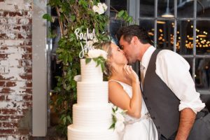 bride and groom kissing next to large five-tier wedding cake