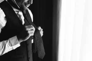 a close up of a groom tying his tie