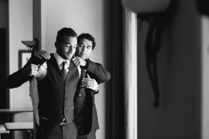 Close up of a groom putting on his tux jacket before his wedding