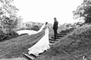 photo of a bride and groom with the bride's veil flowing in the wind