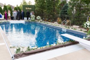 Backyard wedding with pool and gorgeous green and white flower arrangements around it