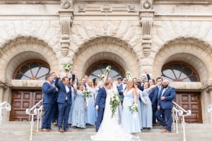Bridesmaids and groomsmen pose excitedly with just married couple