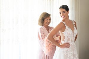 the mother of the bride helped the bride into her wedding gown